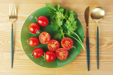 Sliced and whole cherry tomatoes with parsley on a green plate.