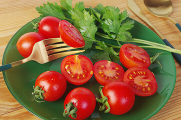 Sliced and whole cherry tomatoes with parsley on a green plate.