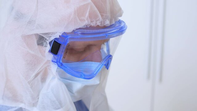 Close-up of a doctor's face in goggles and a mask. A medical worker in a disposable washing gown and protective goggles with a mask works in an infected area or before an operation. Caronovirus.