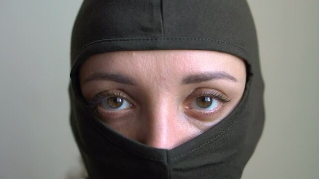 Female portrait of young girl wearing khaki balaclava, only eyes are visible, mandatory conscription, military, feminism, equality concept
