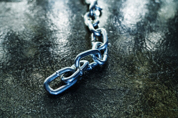 Links of a metal chain on a dark floor background. Selective focus. Close-up