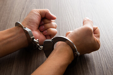 Arrested criminal hands locked in handcuffs.