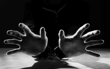 Arrested criminal hands locked in handcuffs.
