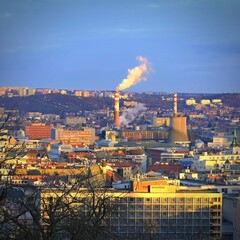 Steaming chimneys with houses in the city. Concept for environment and industry. Background with city landscape at sunset. Brno - Czech Republic - Europe.
