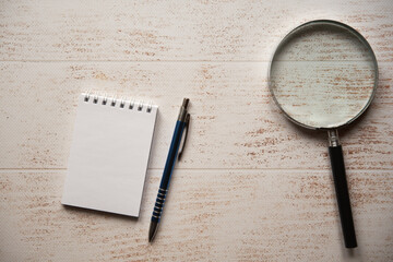 notes, lupa i długopis na drewnianym stole