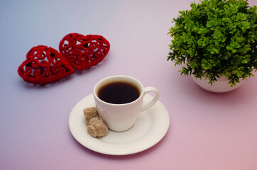 Fragrant coffee in a small cane sugar coffee cup with a pair of red hearts on a pink-blue background.