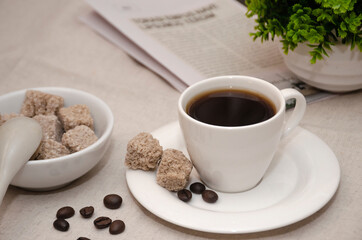 Aromatic coffee with cane sugar and morning newspaper on a wooden table.