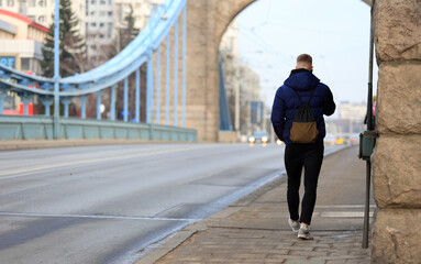 Mężczyzna z torebką spaceruje mostem Grunwaldzkim nad Odrą we Wrocławiu.