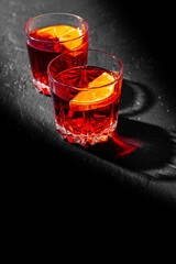 Two glass of cold alcohol cocktail drink on black background with copyspace. Negroni cocktail with orange on a black background.