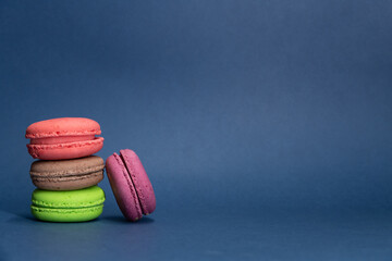 Close-up view of group of colourful french macarons lying on blue background. Pastry-shop. Copy space for your text. Confectionery theme.