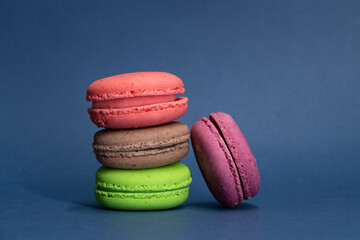 Close-up view of group of colourful french macarons made from whey protein lying on blue background. Sports nutrition store. Nutritional supplement theme.