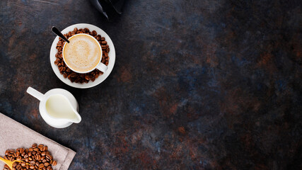 Cup of coffee and coffee beans on a dark background. Ingredients for making coffee with milk. Top...