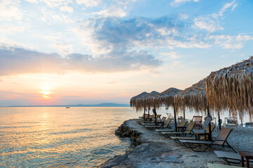 Beautiful sunset seascape with beach chairs and umbrella on the coast, Greece