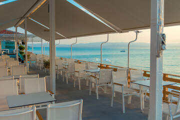 Range of wooden table and white chair for relaxation at restaurant near sea