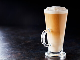 Latte macchiato coffee on a dark background. Glass of latte macchiato, side view. Copy space