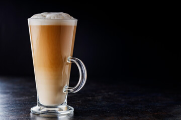 Latte macchiato coffee on a dark background. Glass of latte macchiato, side view. Copy space