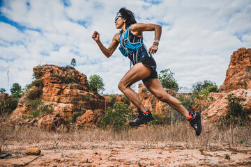 Young woman ultra trail marathon runner running through the rock mountain