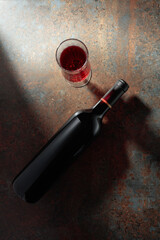 Glass and bottle of red wine on a rusty metal background.