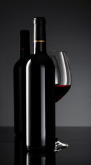 Bottle and glass of red wine on a black background.