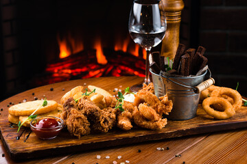 take away food mozzarella sticks, onion rings, french fries, chicken nuggets and sauce on a wooden...