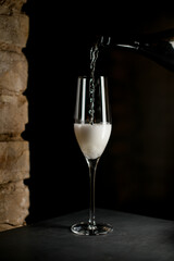 champagne glass into which white sparkling wine is poured from a bottle.
