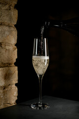 champagne glass into which white tasty sparkling wine is poured from a bottle.