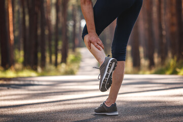 Woman feeling pain of her leg during jogging. Calf muscle cramp. Underestimating the warm-up exercise before running - obrazy, fototapety, plakaty