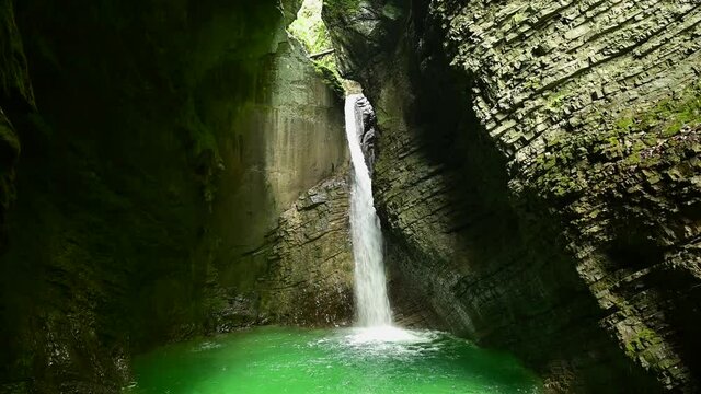 Crystal clear waterfall in a cave flooded with sunlight and blue water