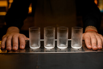 group of misted glasses and hands of bartender nearby