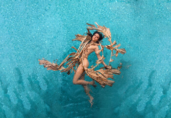Top view of a beautiful young sexy woman floating elegant relaxed in dried up leaves of a banana...
