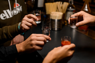 Male hands toasting and cheer with glasses of vodka and liqueur