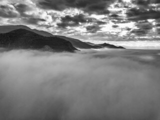 Fototapeta na wymiar Aerial view of a mountain in the fog at sunrise, Tuscany, Italy.