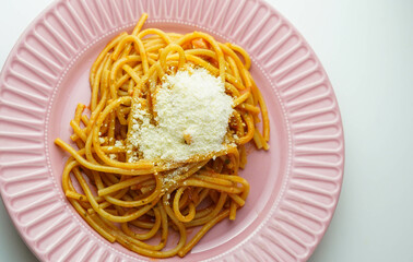 Un plato rosado de espaguetis frescos con salsa de tomate y queso parmesano