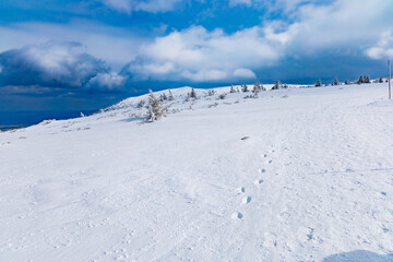 Fototapeta premium Snowy landscape of mountain trails and hills at cloudy morning