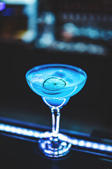 Blue lagoon cocktail with blue curacao liqueur, vodka, lime juice and soda on bar counter