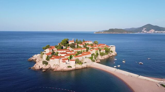 Beautiful island on the southern European coast from drone. Calm blue sea washing the island. Drone shot of Sveti Stefan (Saint Stephen) island in Montenegro.