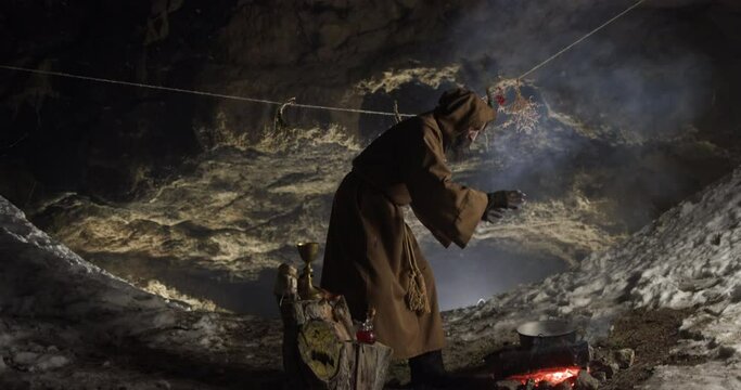 Senior hermit preparing magic potion in cave