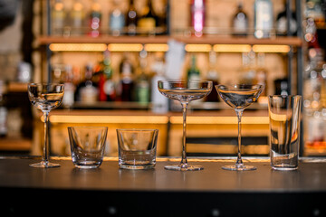 front view of wine glasses and glasses of different shapes and sizes on blurred background
