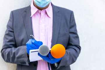 Journalist wearing protective gloves and face mask against coronavirus COVID-19 disease holding...