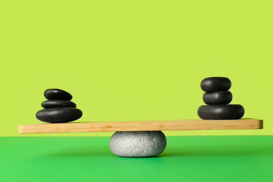 Spa stones on teeterboard against green background. Concept of balance