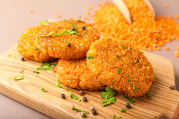 Board with tasty lentil cutlets on table, closeup