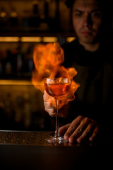 wine glass with beverage on the bar and fiery flame is in the background