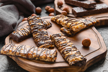 Board with tasty chocolate nut bars on dark background