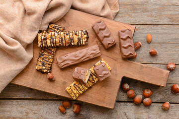 Board with tasty chocolate nut bars on wooden background