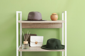 Shelving unit with accessories and reed diffuser near green wall