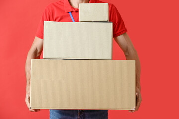 Male courier with parcels on color background