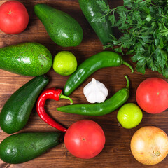 Mexican cuisine ingredients - chili, jalapeno, avocado, lime, onion, tomato, garlic and cilantro. Ingredients for guacamole, top view, flat lay