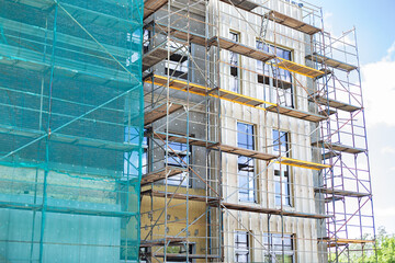 Building under construction against blue sky. New high-rise building under construction with brick work and wooden scaffolding. Concrete building under construction. 
