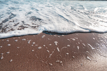 Smooth sandy at the beach and beautiful wave in background. Soft wave blue ocen and sandy beach. Small waves lapped the beach