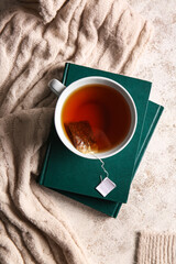 Books, cup of tea and sweater on light background